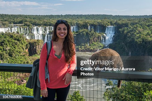 Portrait of female tourist posing with¬ÝSouth American¬Ýcoati¬ÝNasua¬Ýnasua against¬ÝIguazu Falls, Parana, Brazil